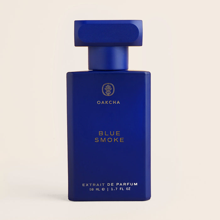 Front view of Blue Smoke perfume bottle showing matte deep-blue rectangular bottle with gold lettering on a cream background