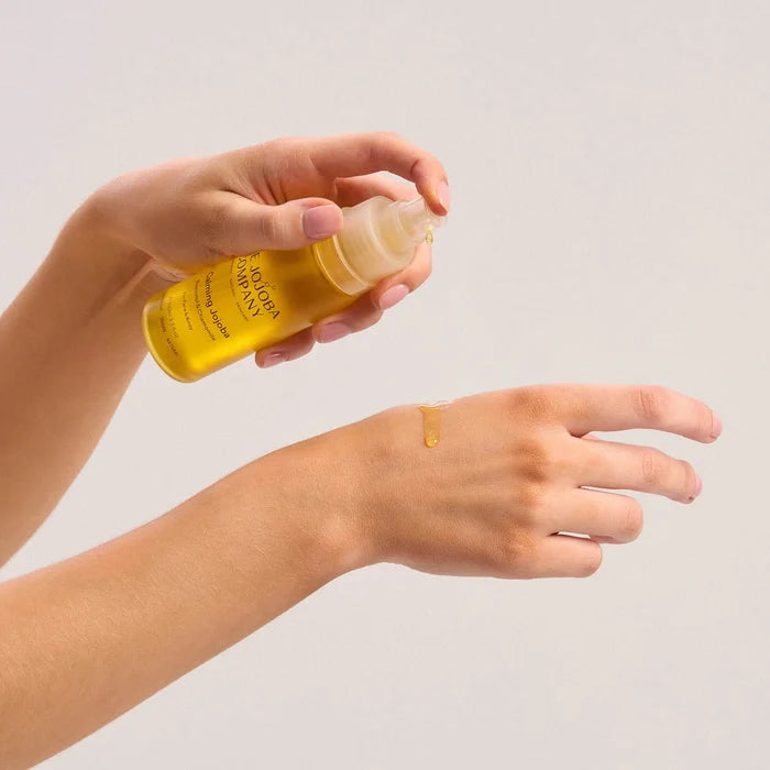 Person pumping a small dollop of calming jojoba onto their other hand.