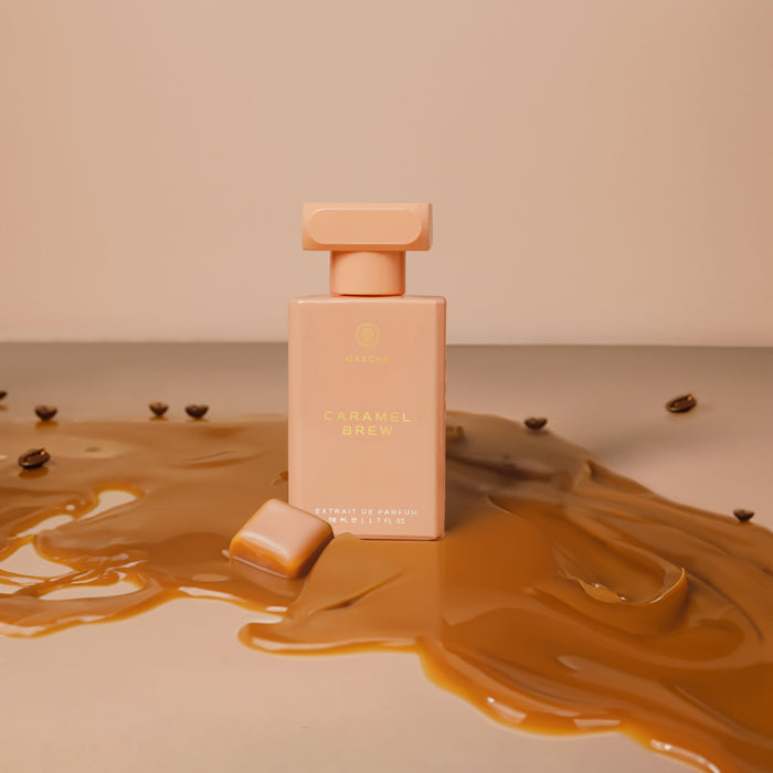 Front view of Caramel Brew perfume showcasing a frosted rectangular bottle with gold cap and spilled caramel on a beige background
