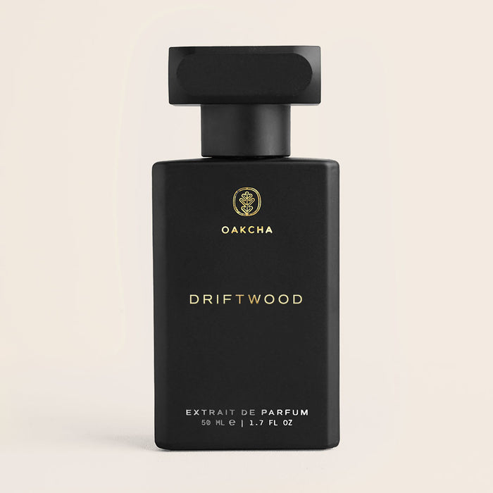 Front view of Driftwood 50ml perfume bottle showcasing matte black rectangular bottle with Oakcha gold logo on pale beige background