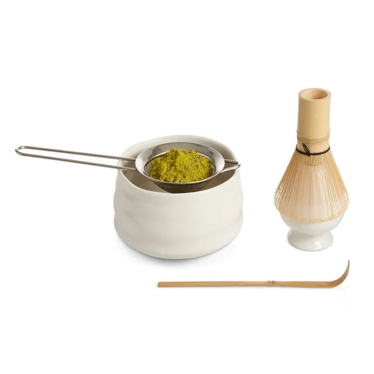 Tea-making set with ceramic whisk holder, metal tea strainer, and wooden whisk on a white background