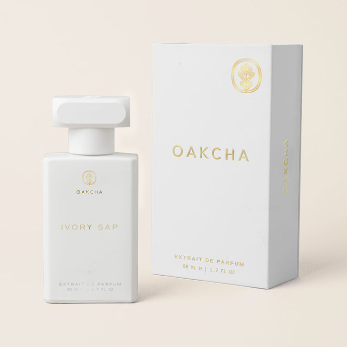 Three-quarter front view of Ivory Sap perfume bottle and box showcasing white minimalist bottle with gold logo on pale beige background