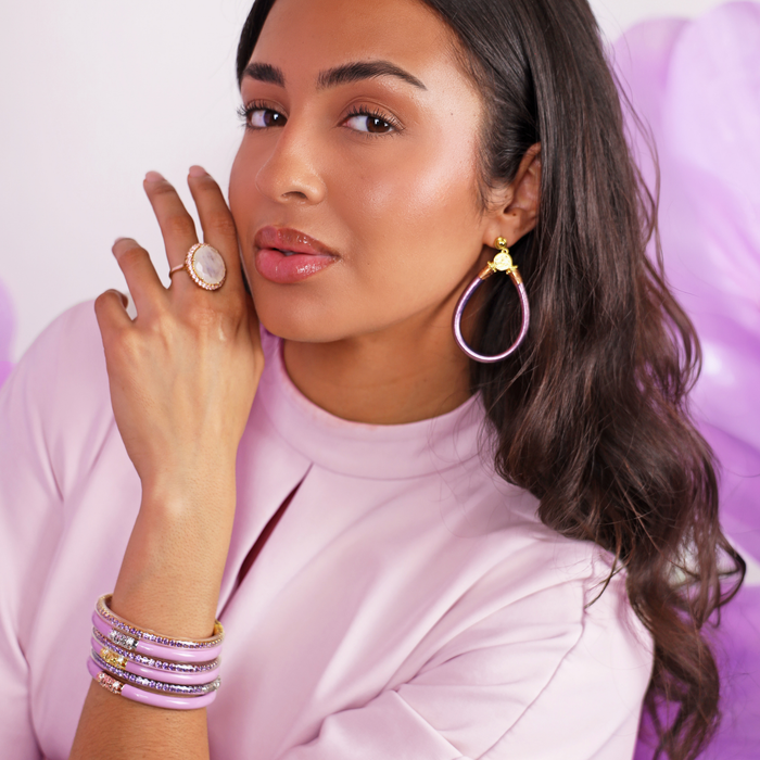 a woman with long hair wearing a pink shirt and purple earrings
