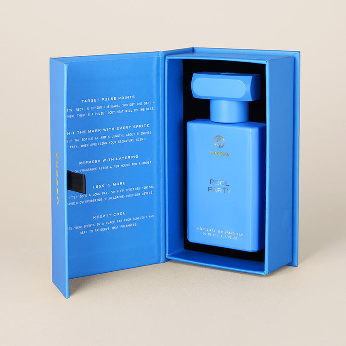 Three-quarter view of Pool Party perfume bottle in blue rectangular bottle with matching open presentation box on beige background
