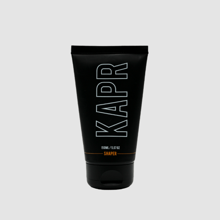 KAPR Shaper – zwarte tube met wit logo op grijze achtergrond, professionele barbershop styling.