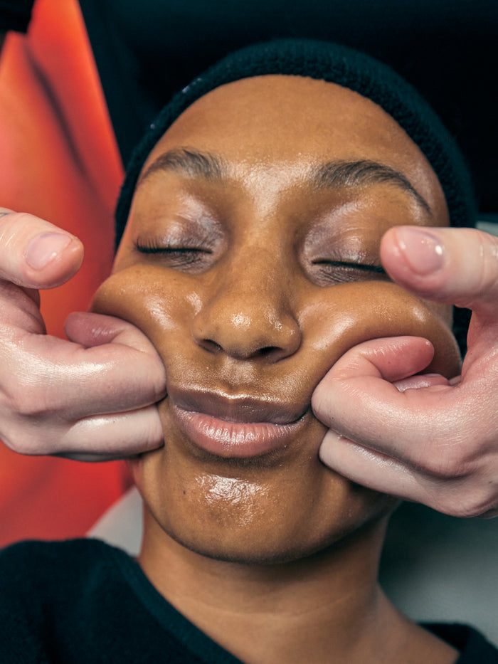 a woman with her eyes closed and hands on her cheeks