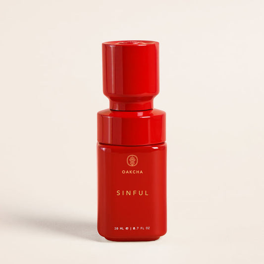 Close-up front view of Sinful perfume oil bottle showing glossy red stacked cap, gold Oakcha logo and 20 ml marking on cream background