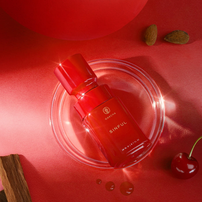 Front view of Sinful Perfume Oil bottle showing red glass and cap on a red background with cherry and spices