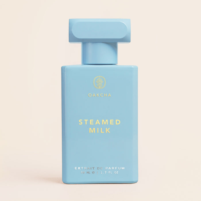 Front view of Steamed Milk bottle showing pale blue rectangular bottle with block cap and gold text on beige background