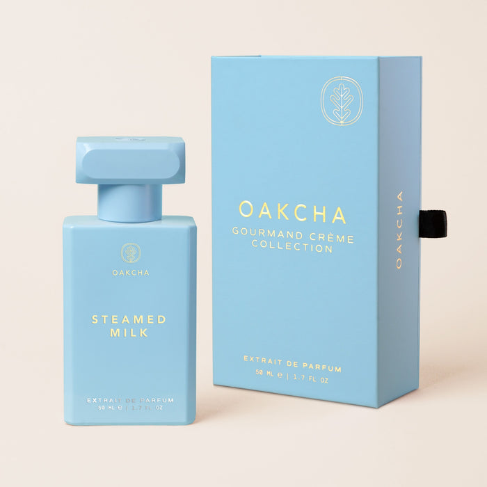Front view of Steamed Milk bottle and box showing powder blue bottle with gold logo on beige background