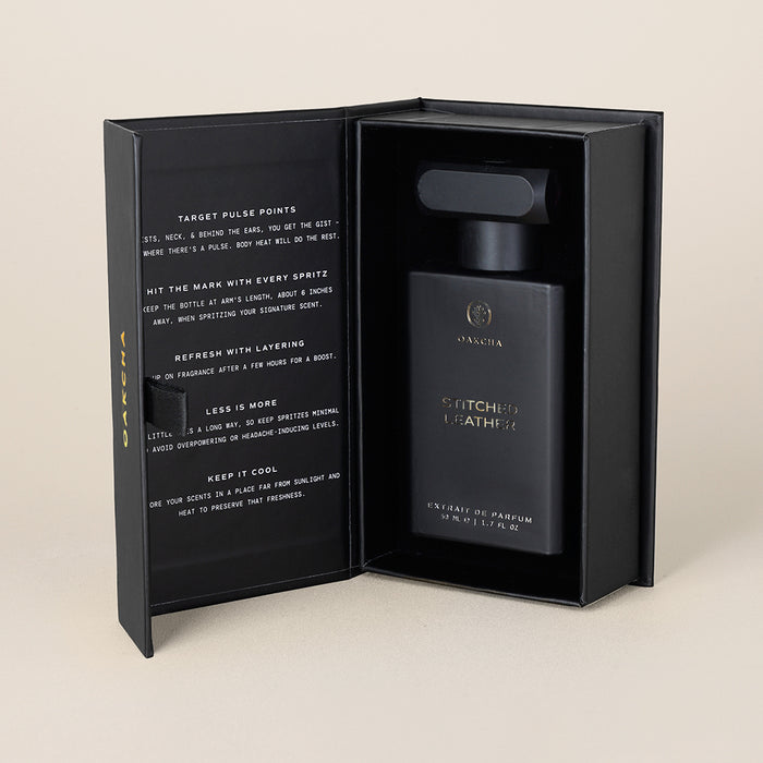 Front view of Stitched Leather Extrait de Parfum in an open black box showcasing the matte black bottle on a neutral background