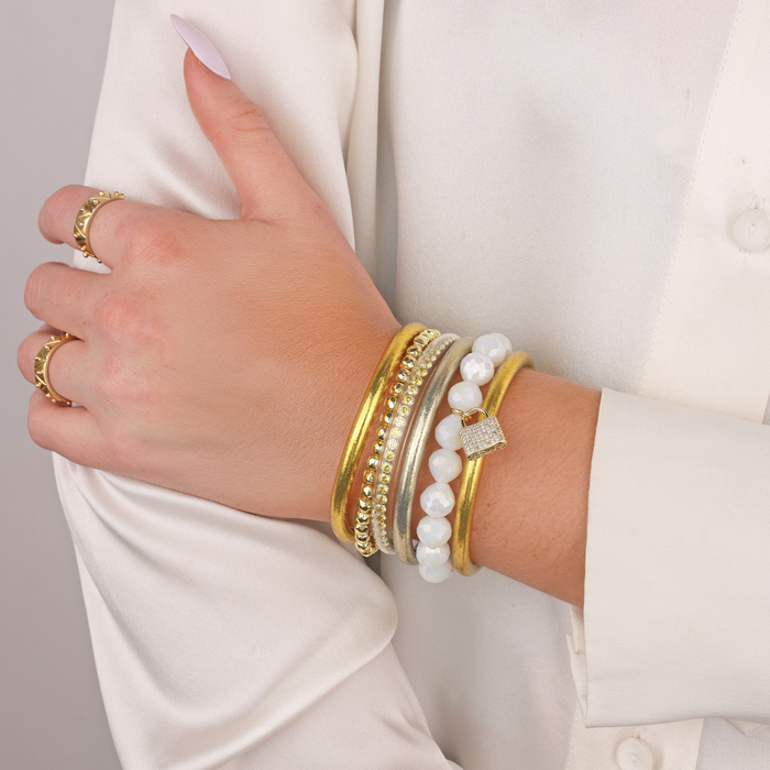 a hand with gold bracelets and rings