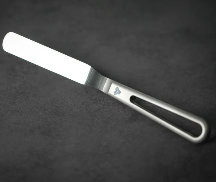 An offset spatula with a gray handle and blade against a dark background.