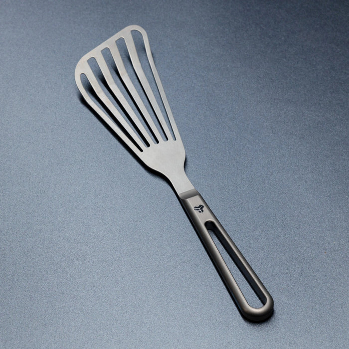 Titanium spatula with a black handle on a gray background