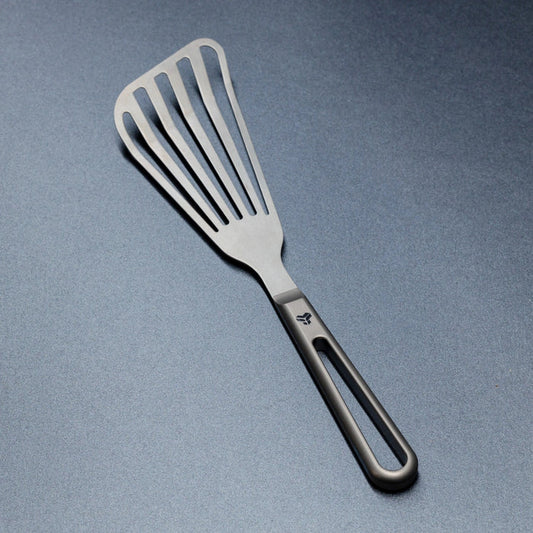 Titanium spatula with a black handle on a gray background