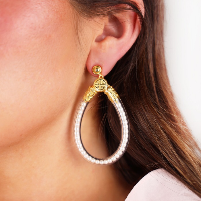 a woman wearing a gold and white earring