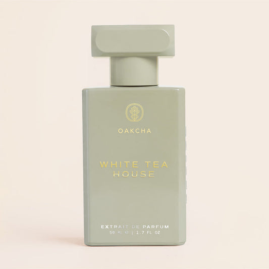 Front close-up of White Tea House 50ml perfume, matte sage-green rectangular bottle with gold logo on beige background